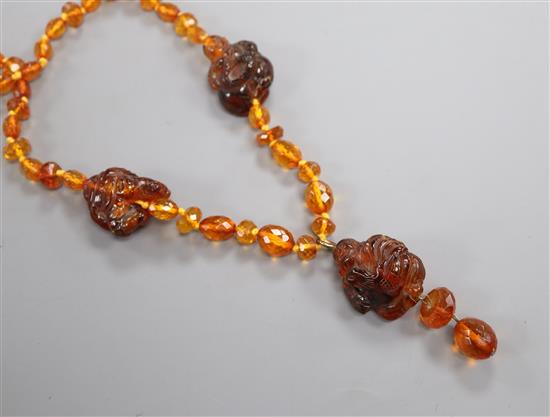 An amber necklace, with facetted beads and three carved Buddha, gross weight, 38 grams, 78cm.
